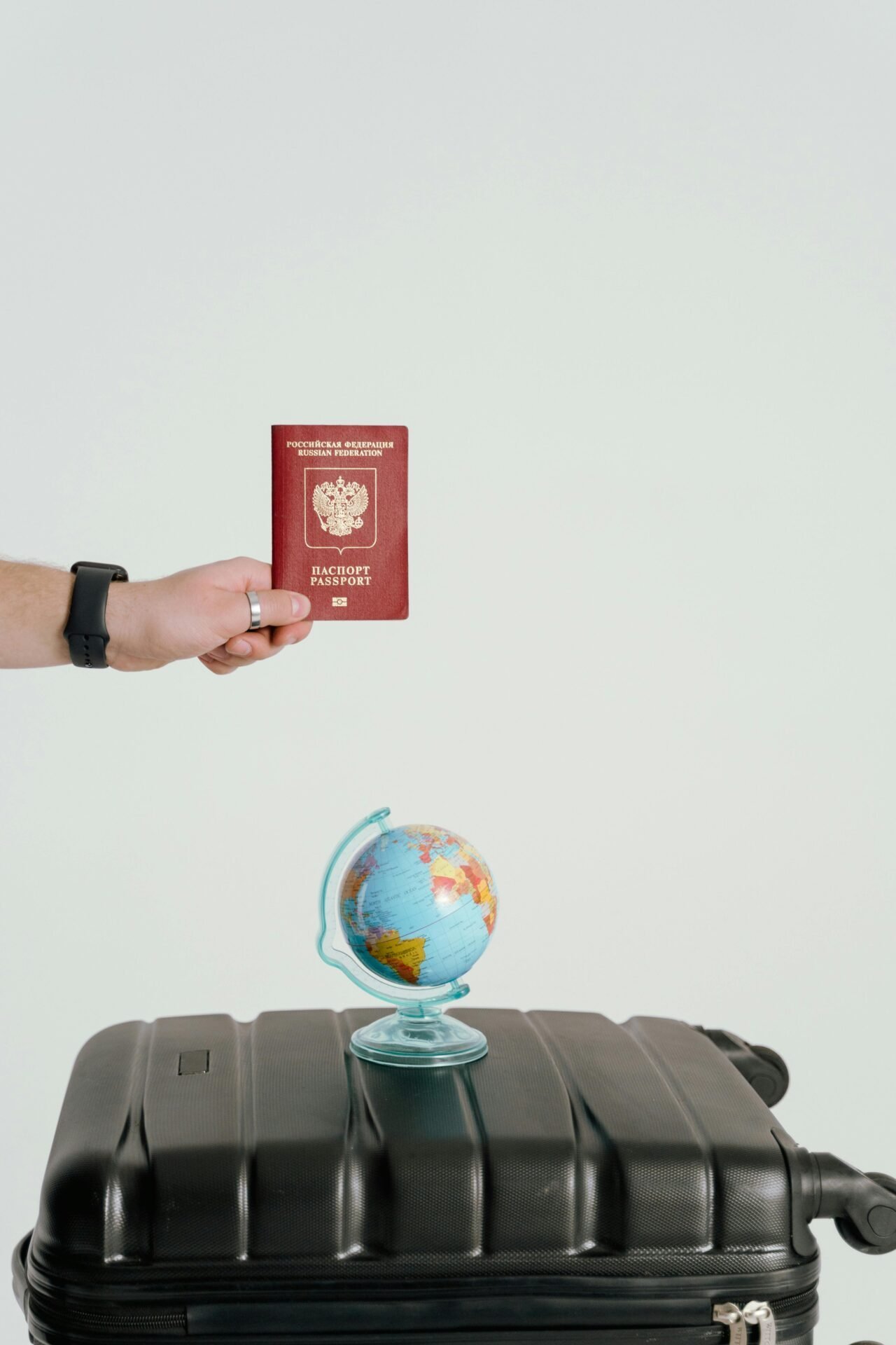 Eine Hand hält einen Reisepass über einem Koffer mit einem kleinen Globus, der die Arbeit in den USA symbolisiert.