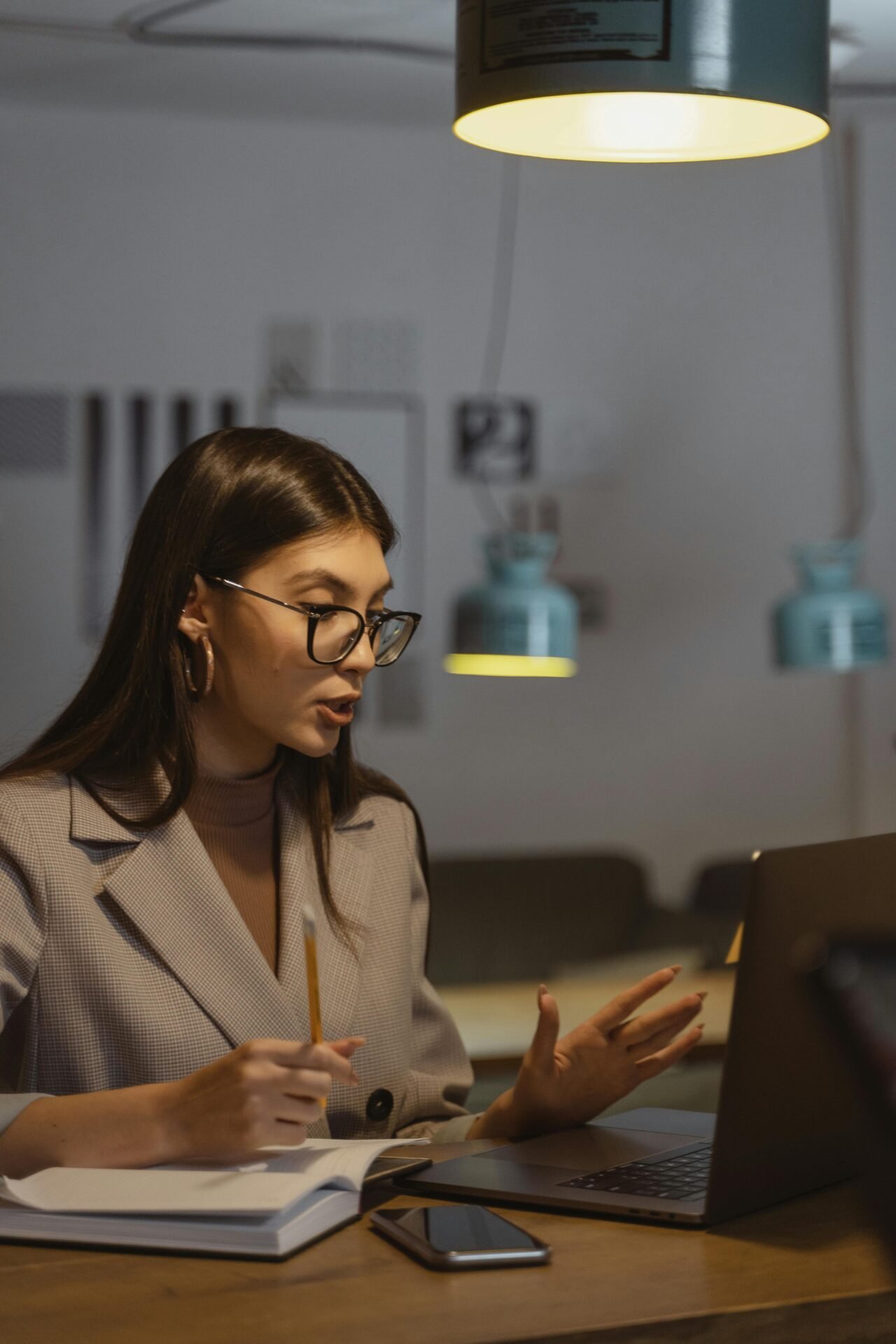 Frau mit Brille an ihrem Schreibtisch, die beim Arbeiten an ihrem Laptop eine geschäftsmäßige Denkweise an den Tag legt.