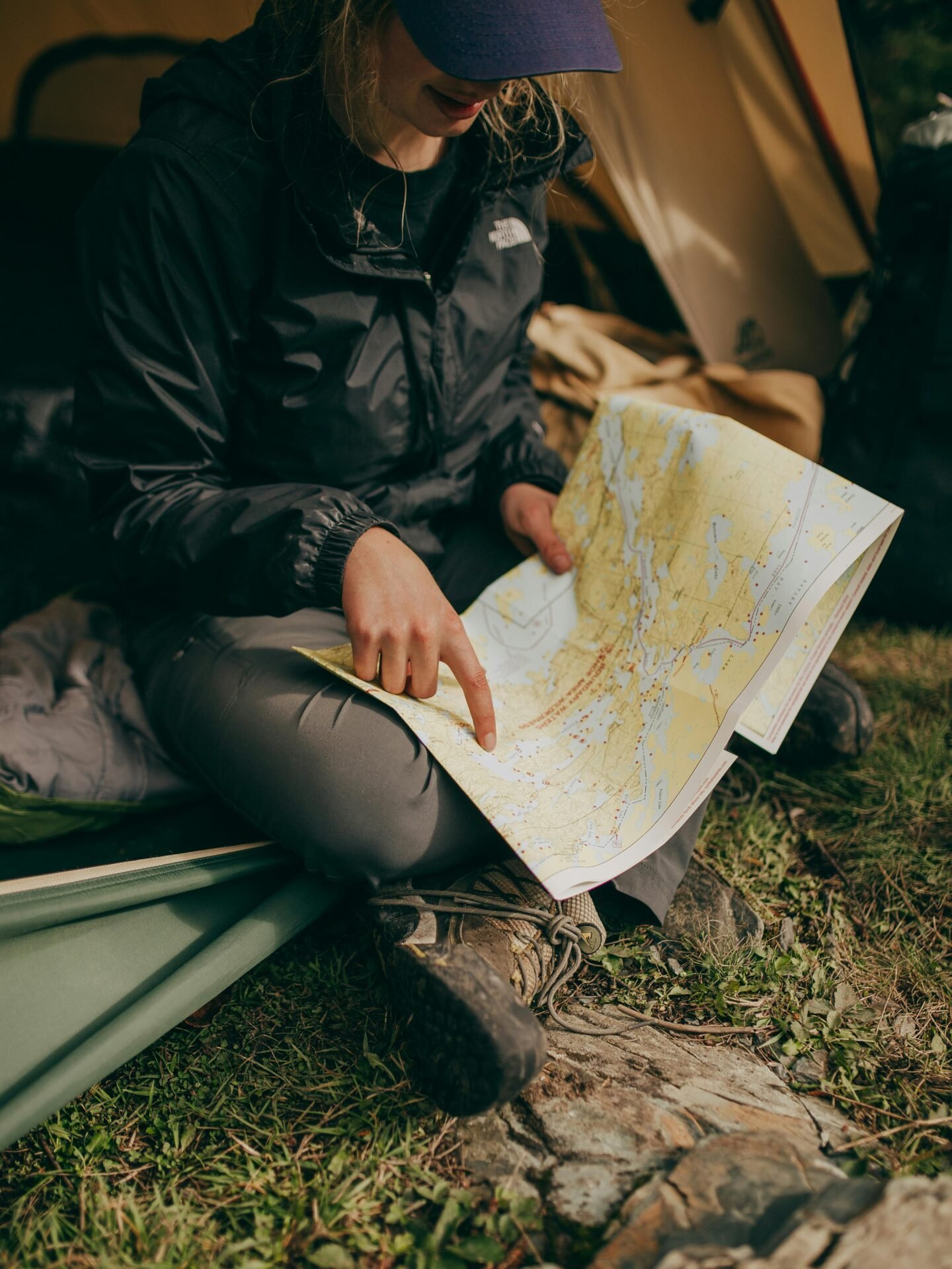 Person am Eingang eines Zeltes, die Camping-Hacks anwendet, während sie eine Karte studiert und auf eine Stelle zeigt.
