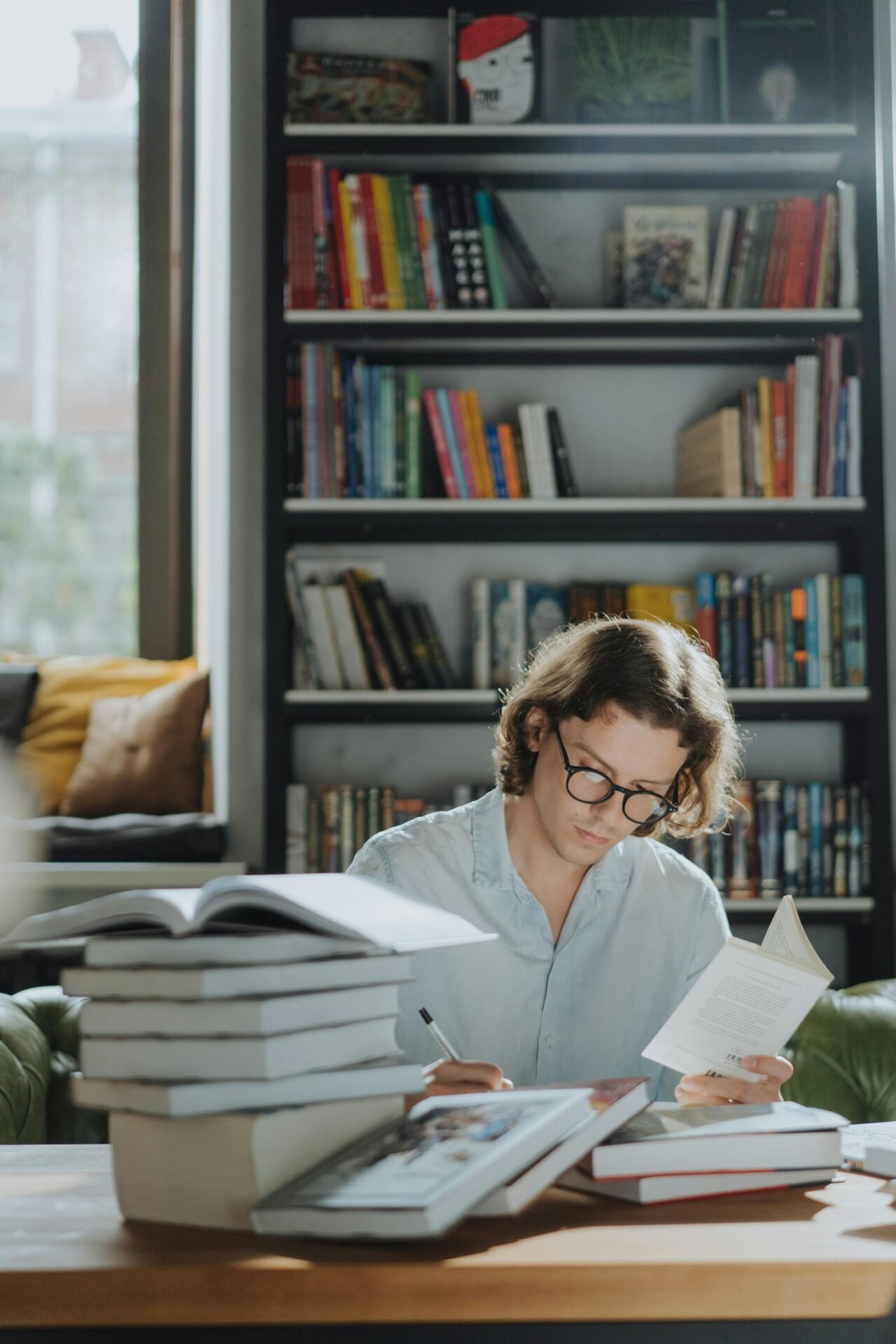 Person liest und macht Notizen, um in einer Bibliothek erfolgreich lernen zu können.