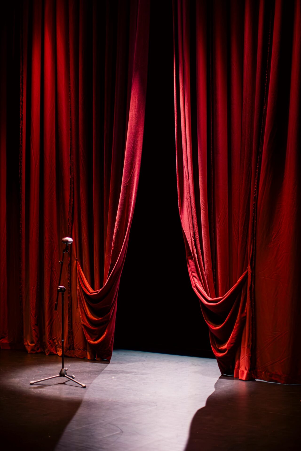 Ein einzelnes Mikrofon steht auf der Bühne und wartet zwischen roten Theatervorhängen auf erfolgreiche Frauen.