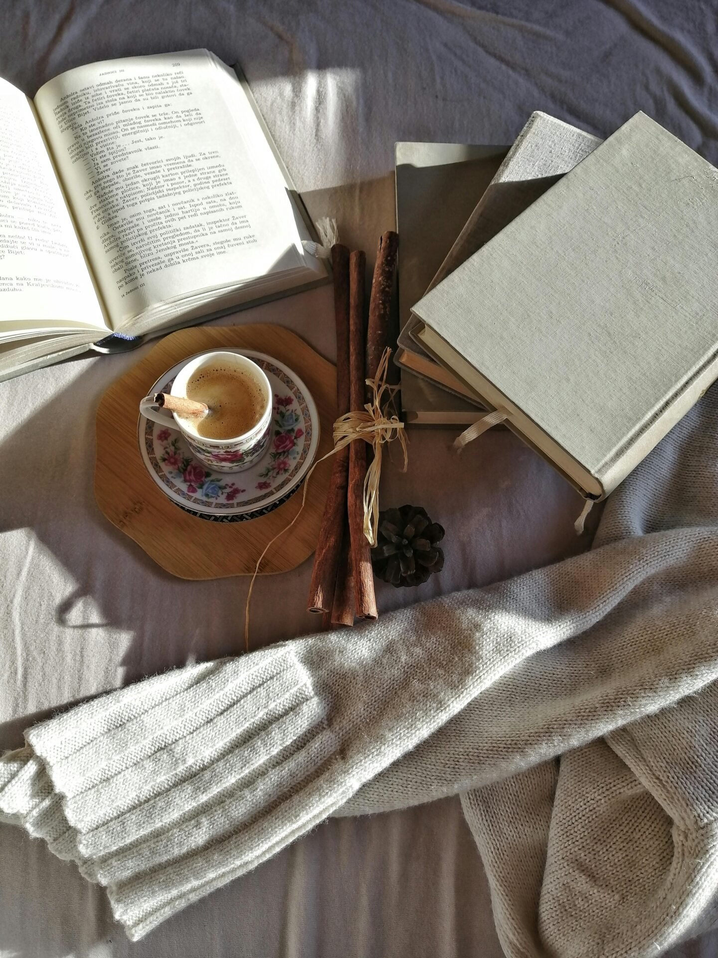 Eine Tasse Kaffee, Bücher und ein Schal – perfekte Sonnenlichtmomente für erfolgreiche Frauen.
