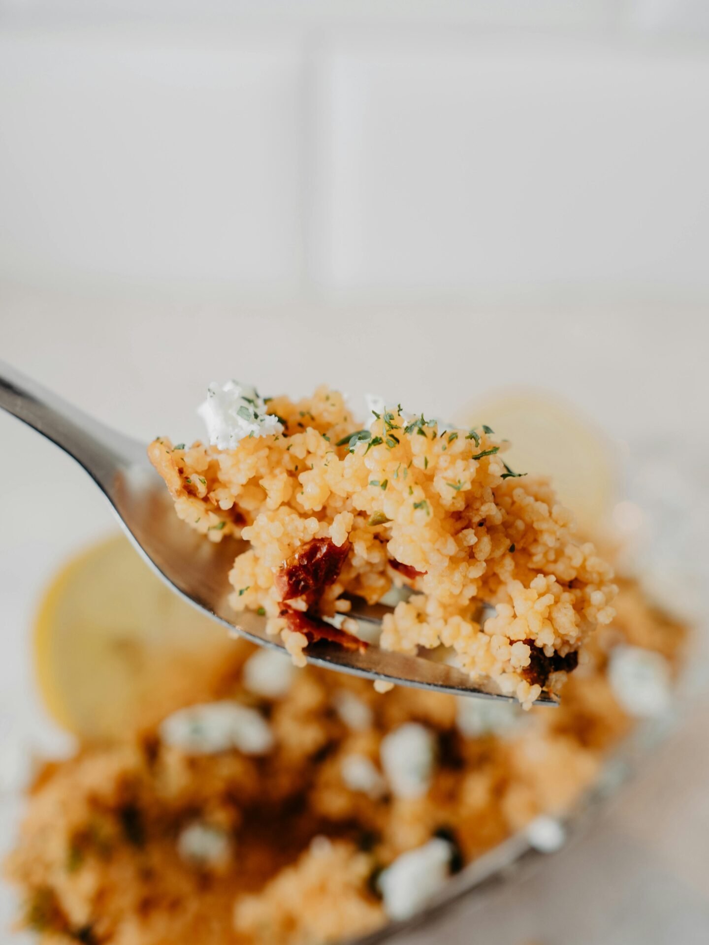 Eine Gabel mit einem Stück Couscous – gesundes Essen für die Arbeit kalt mit Kräutern und Tomaten.