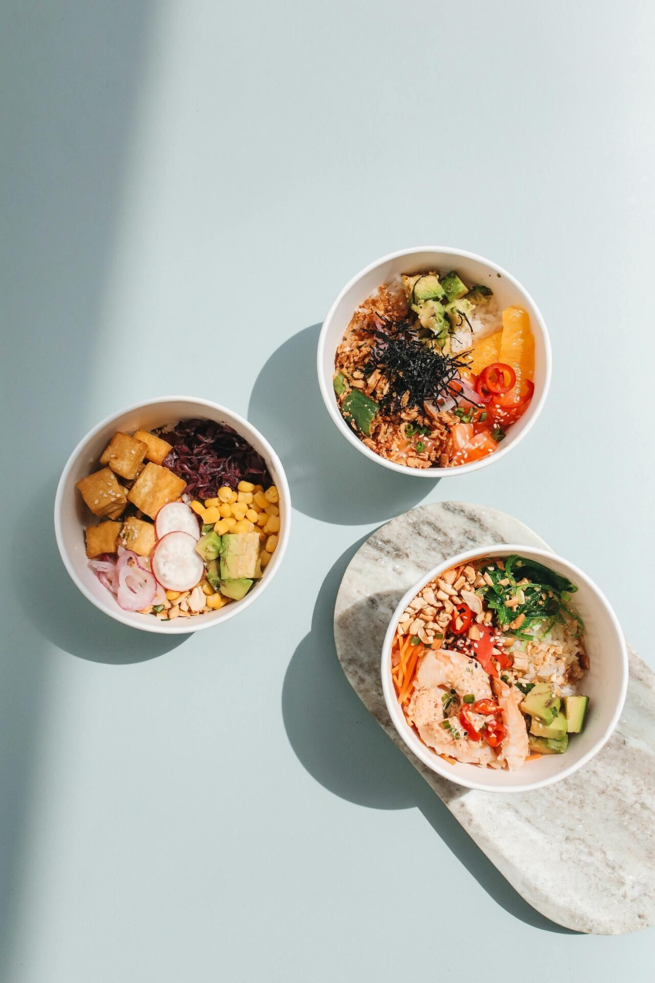 Drei bunte Poke Bowls – gesundes Essen für die Arbeit, perfekt auch kalte Genossen.