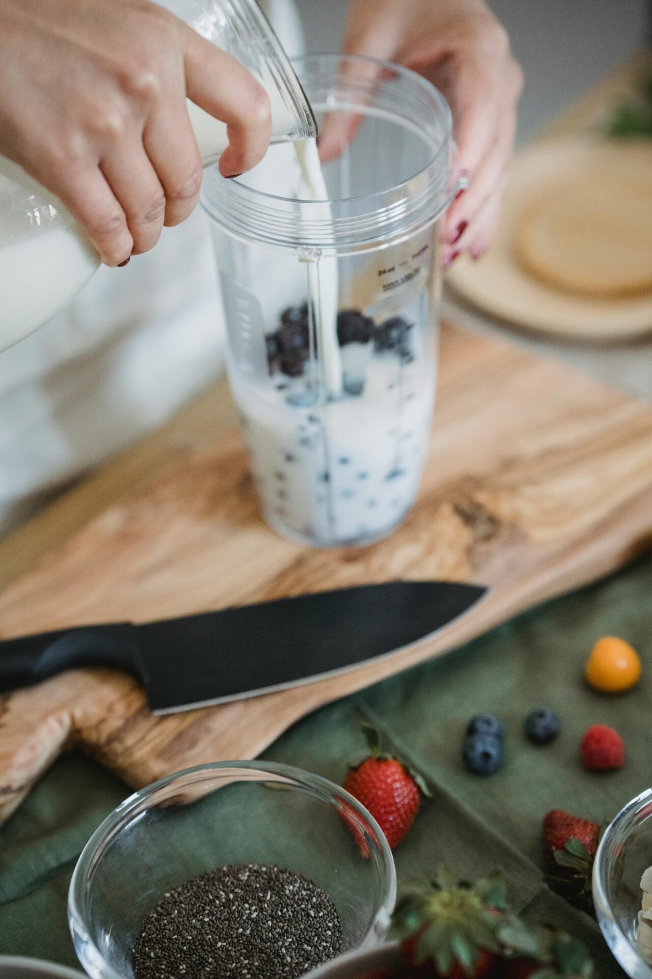 Eine Person bereitet gesundes Essen für die Arbeit kalt mit Milch und Blaubeeren in einem Mixbecher zu.