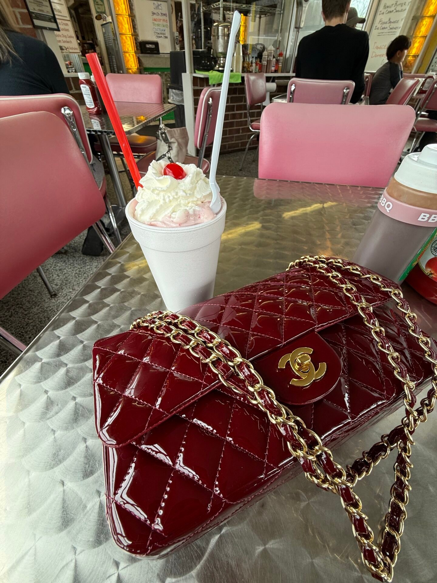 Eine rote Chanel-Handtasche und ein Milchshake deuten auf finanzielle Freiheit auf einem klassischen Esstisch hin.