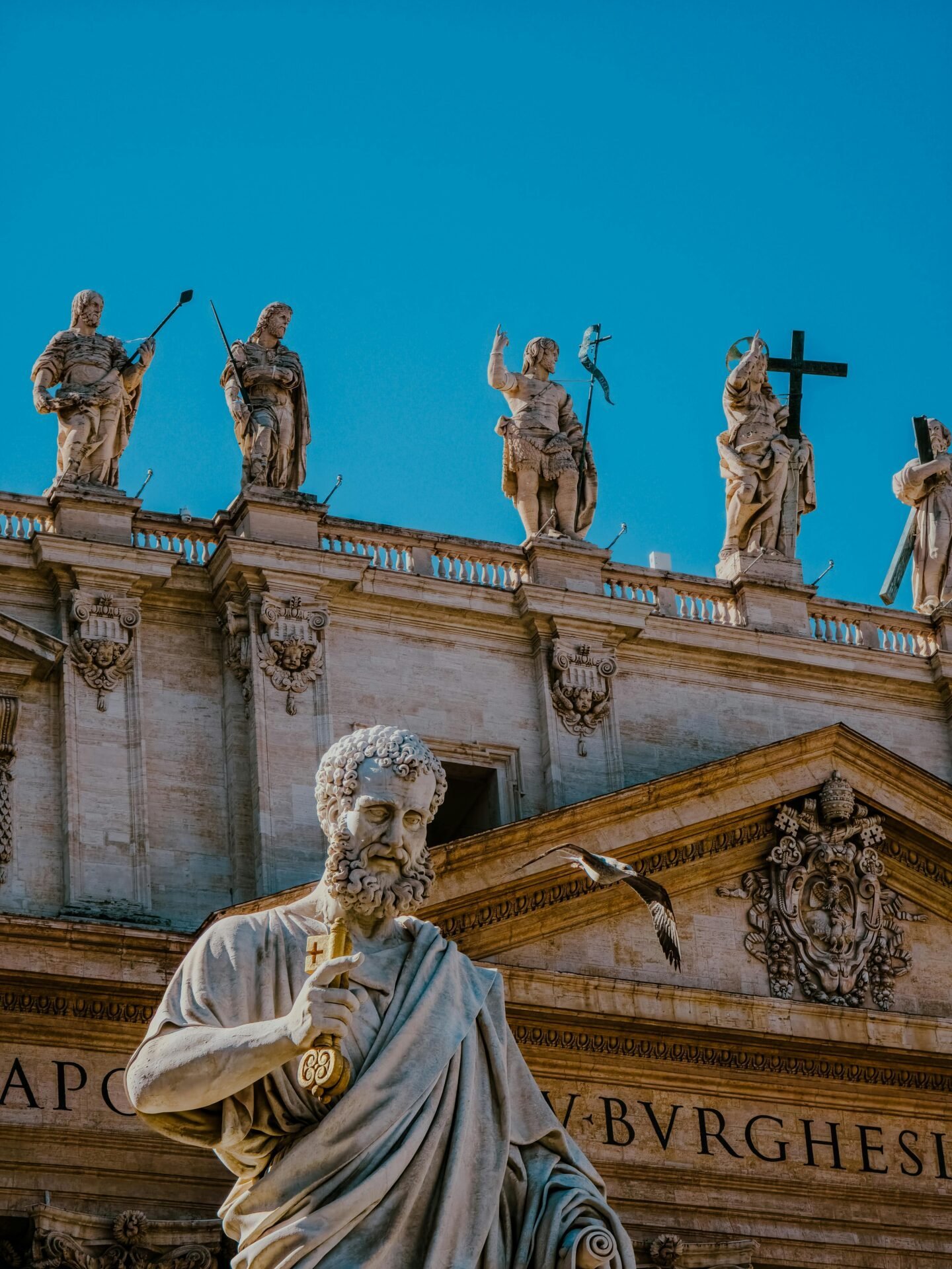 Philosophenstatue auf einer Kathedrale unter blauem Himmel, die an Zitate zum Thema Glück erinnert.