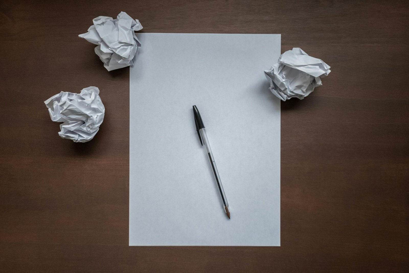 Leeres Papier mit Stift, zerknüllte Kugeln – auf dem braunen Tisch beginnt ein Mentalitätswandel.