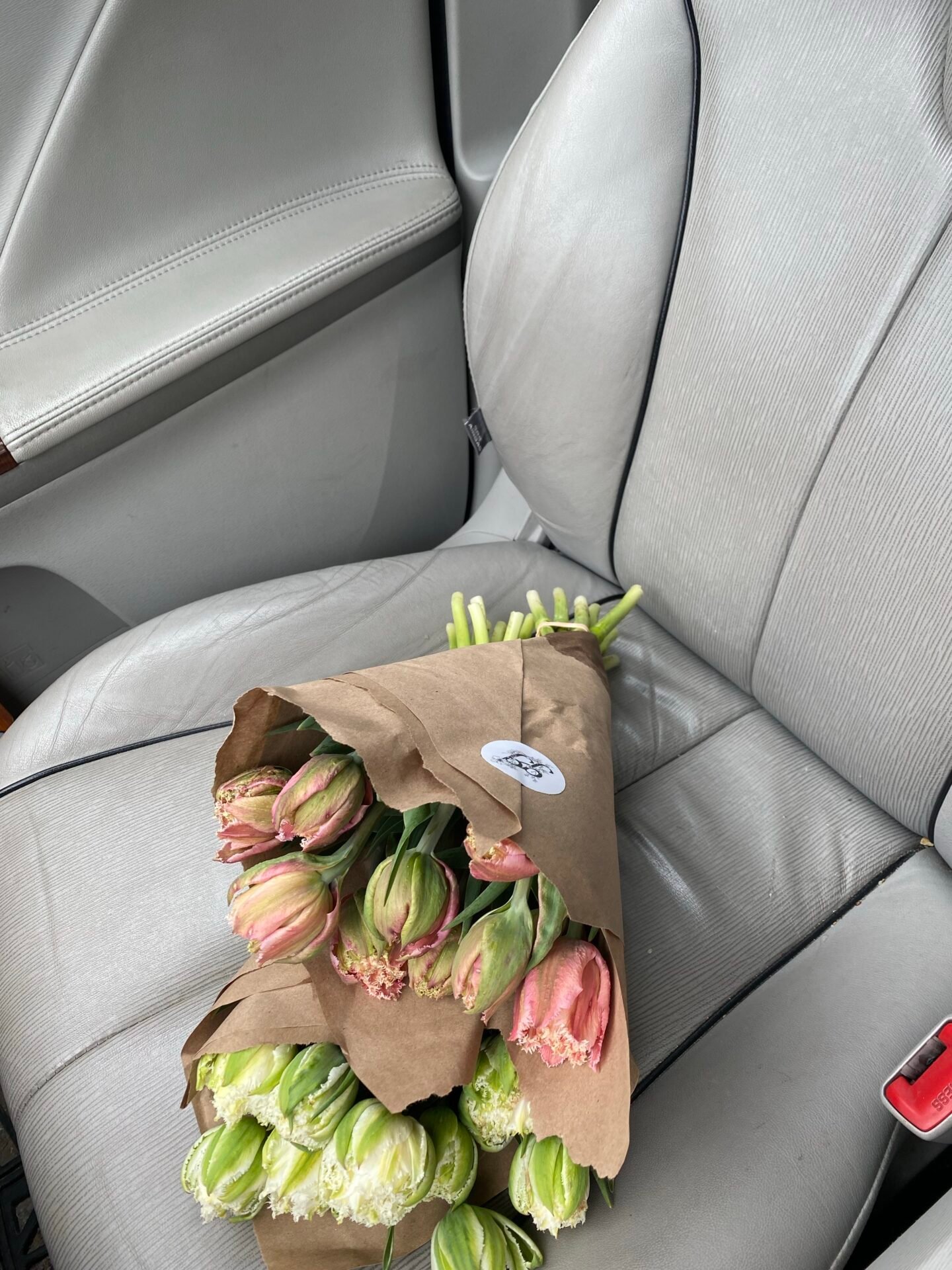 Ein Strauß Tulpen, perfekt für Ihr Online-Geschäft, ruht auf einem grauen Autositz.