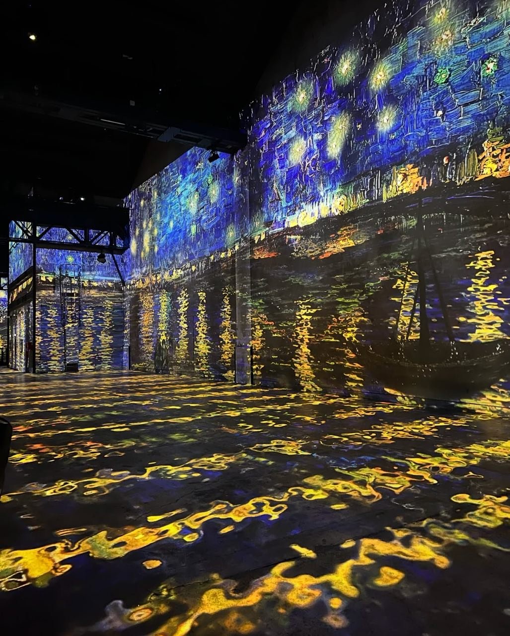 Immersive Pariser Kunstausstellung mit Van Goghs "Sternennacht", die auf Wände und Boden projiziert wird.