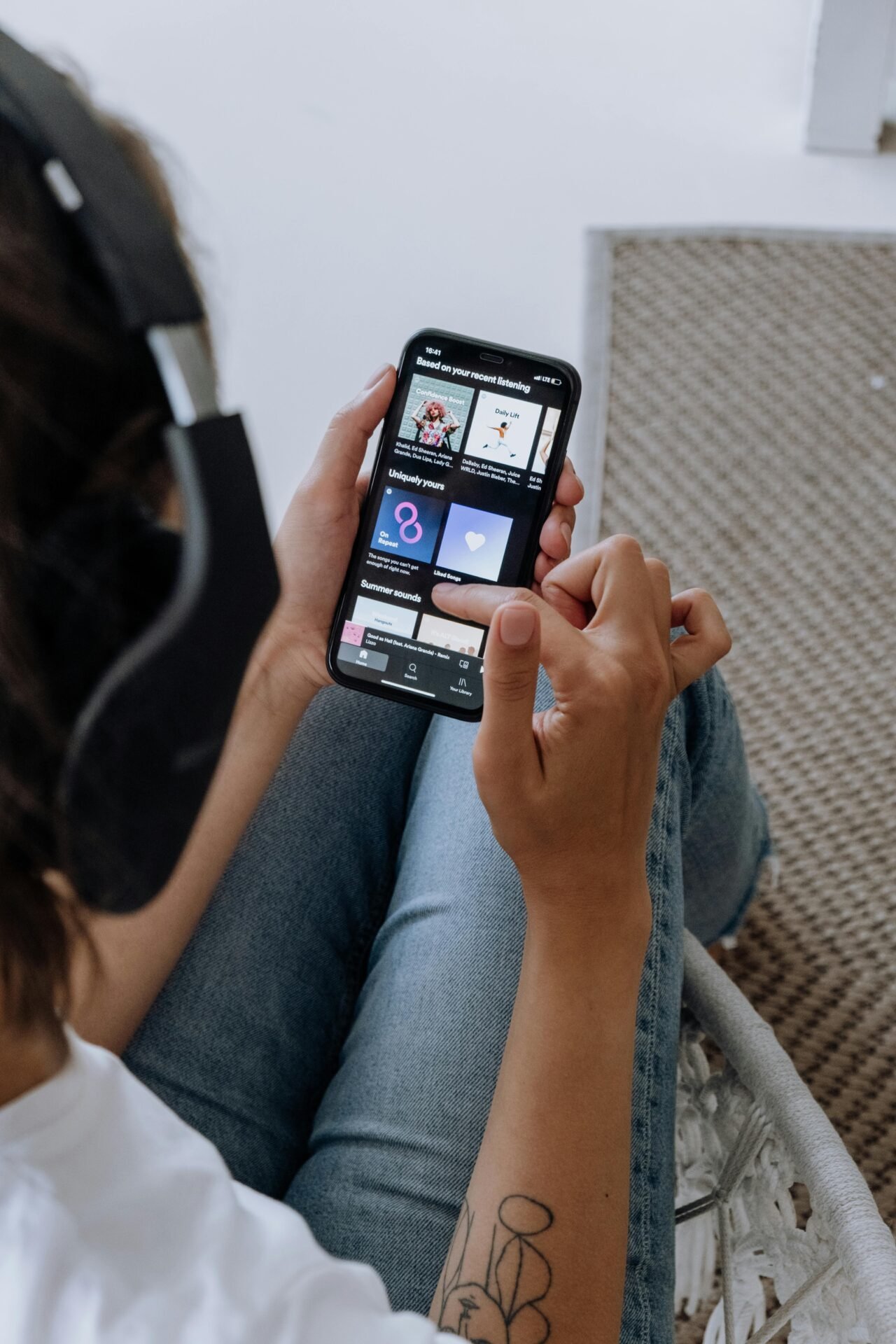 Person hört Musik zur Konzentration per App auf dem Smartphone, sitzend auf einem Stuhl.