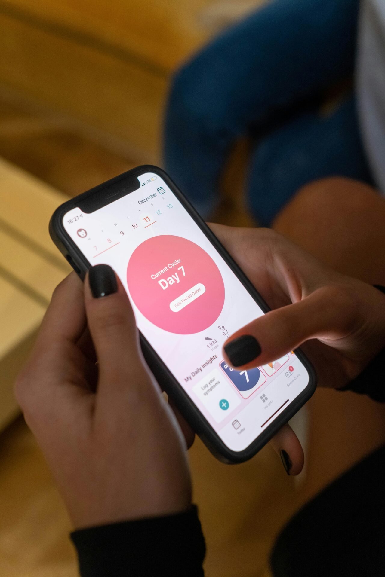 Person hält ein Smartphone mit einer Menstruationszyklus-App, um Zeitfresser im Alltag zu vermeiden.