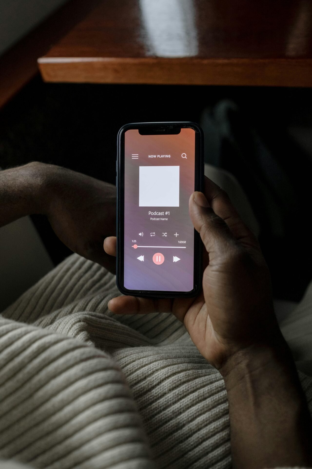 Person hält ein Telefon, auf dem ein Podcast zum Thema „Musik zur Konzentration“ mit Wiedergabesteuerung abgespielt wird.