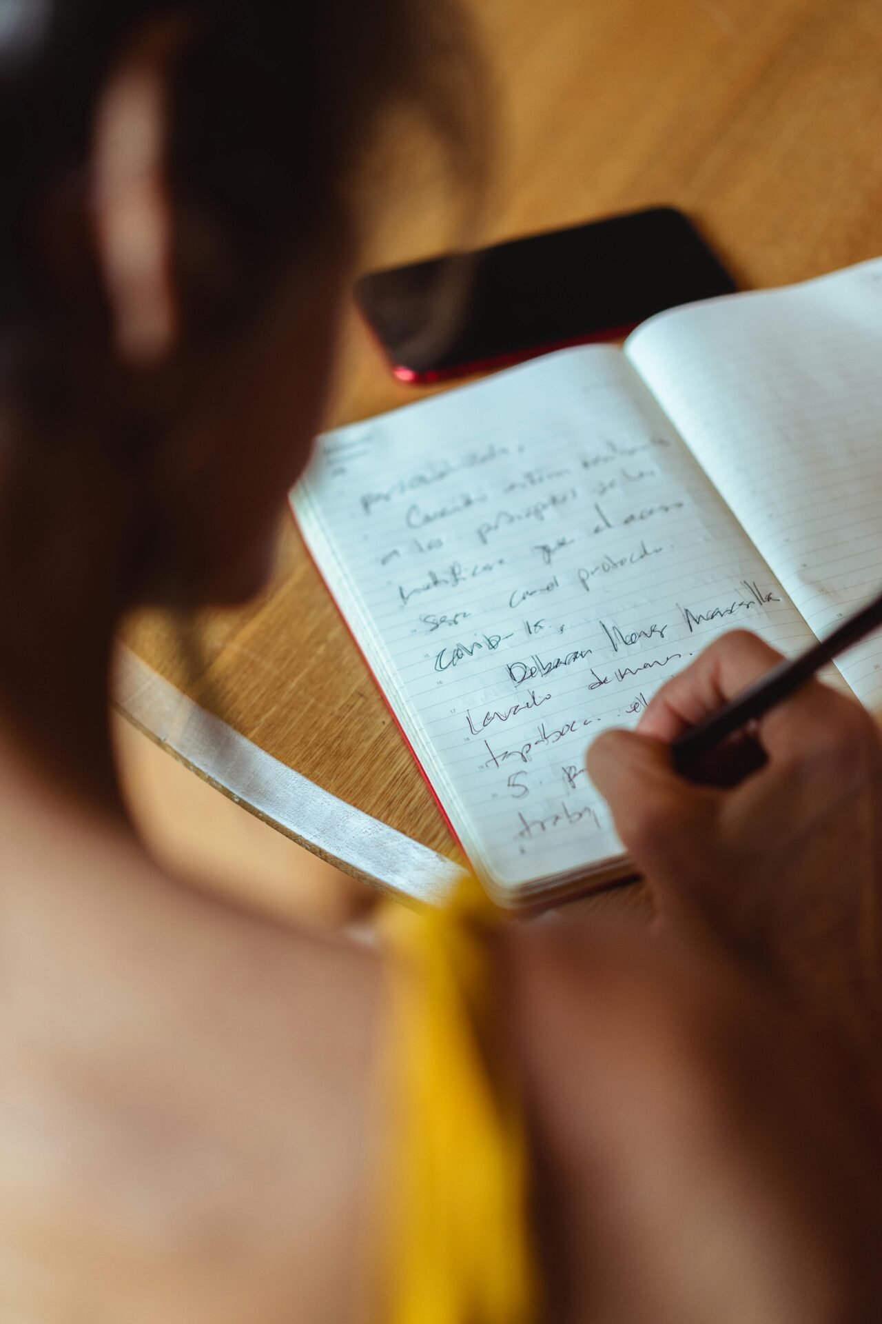 Eine Frau schreibt mit einem Stift in einen Kalender, als würde sie als Teil einer Morgenroutine journaln oder ihren Tag planen.