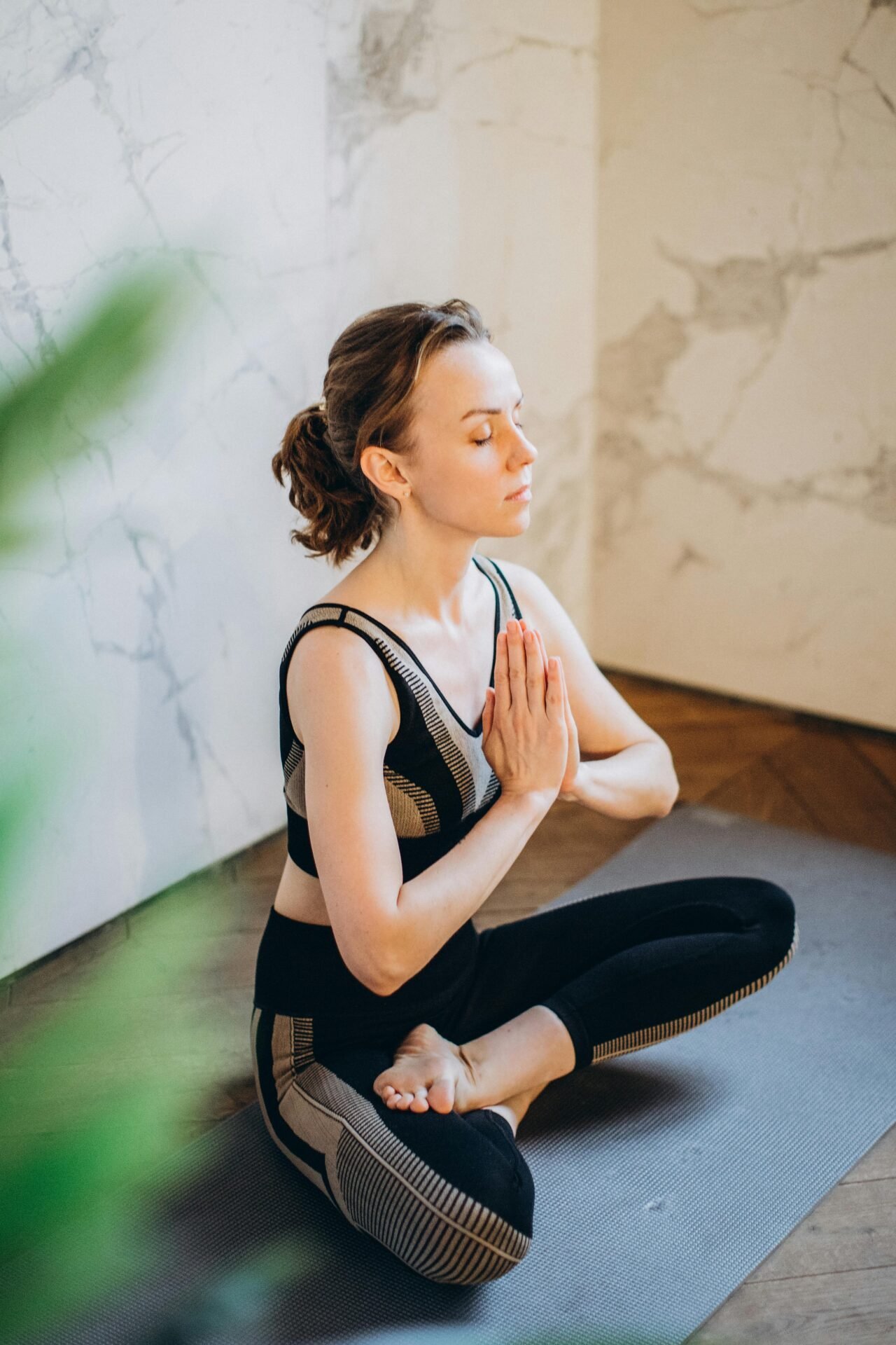 Eine junge Frau in Sportkleidung entspannt beim Yoga.