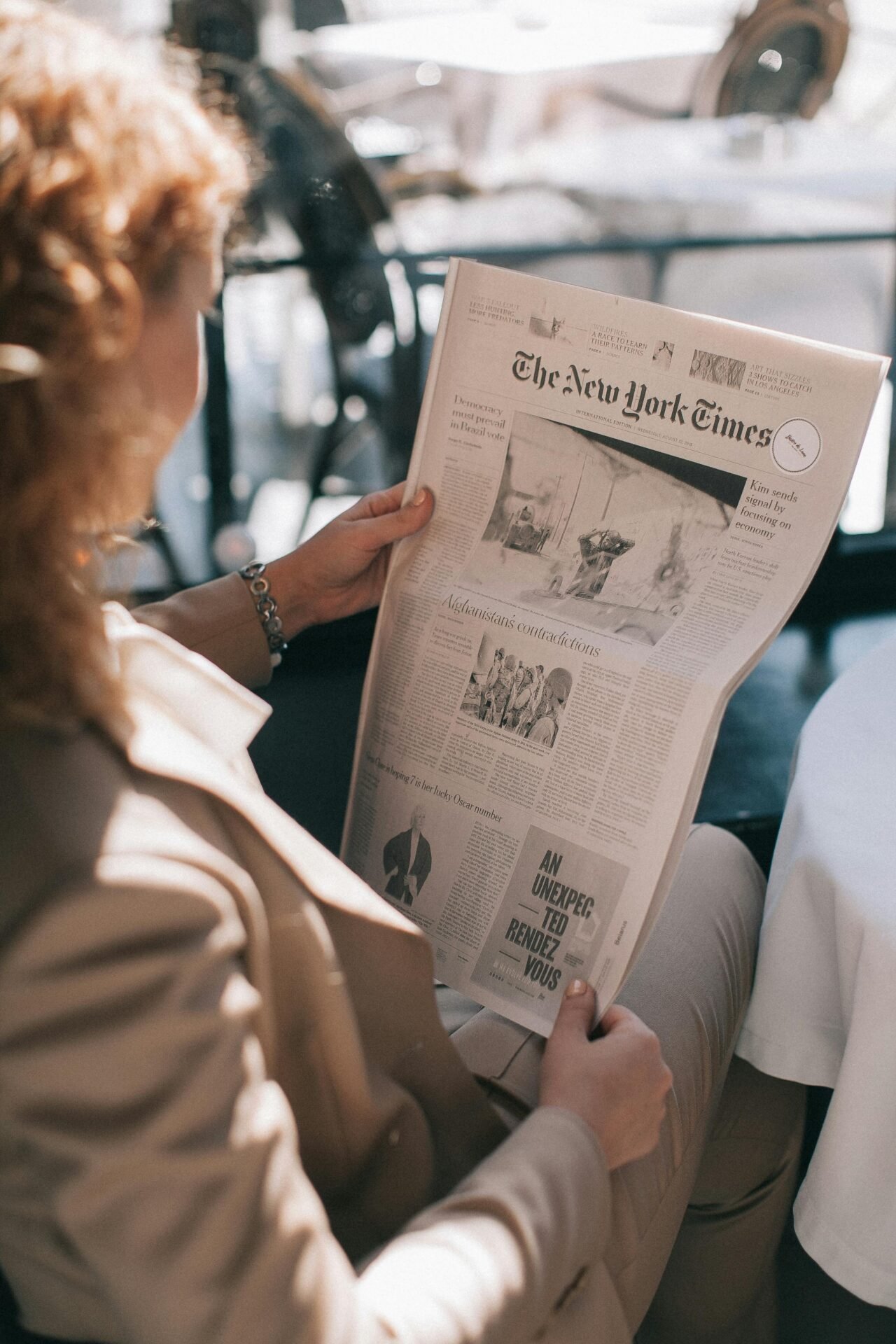 Person in einem hellbraunen Anzug liest die New York Times und pflegt drinnen einen gesünderen Lebensstil.