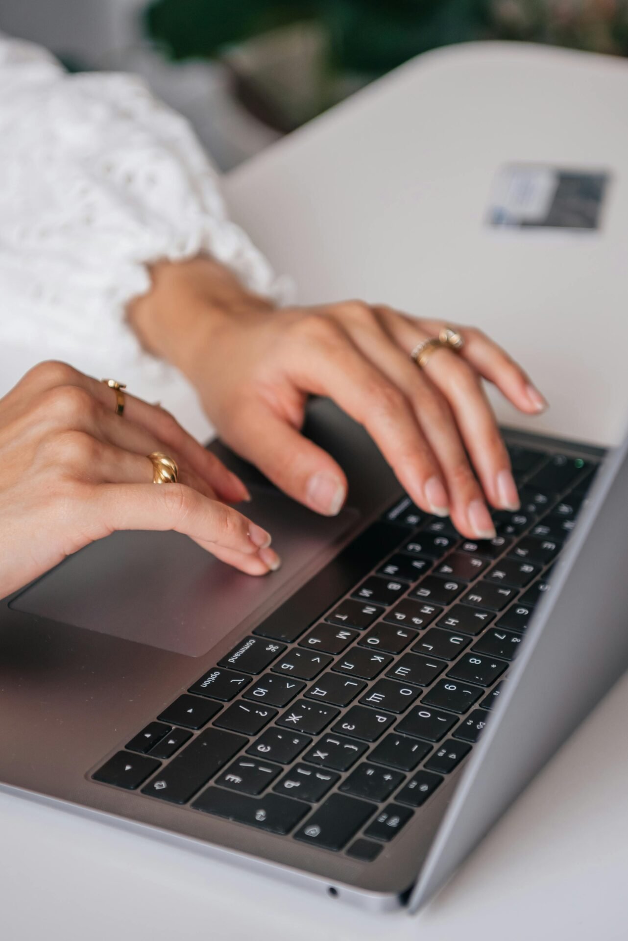 Hände mit Ringen tippen auf einem Laptop, im Hintergrund eine Kreditkarte – das zeigt eine Geschäftsmentalität.