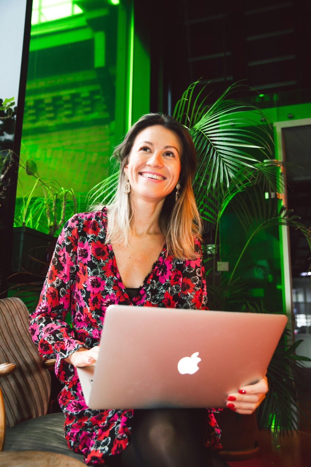 Für viele Menschen dreht sich das Lebensziel zu finden um Karriere - hier zu sehen ist eine Frau, die glücklich an einem Laptop arbeitet, in einem Büro oder Coworking-Space.