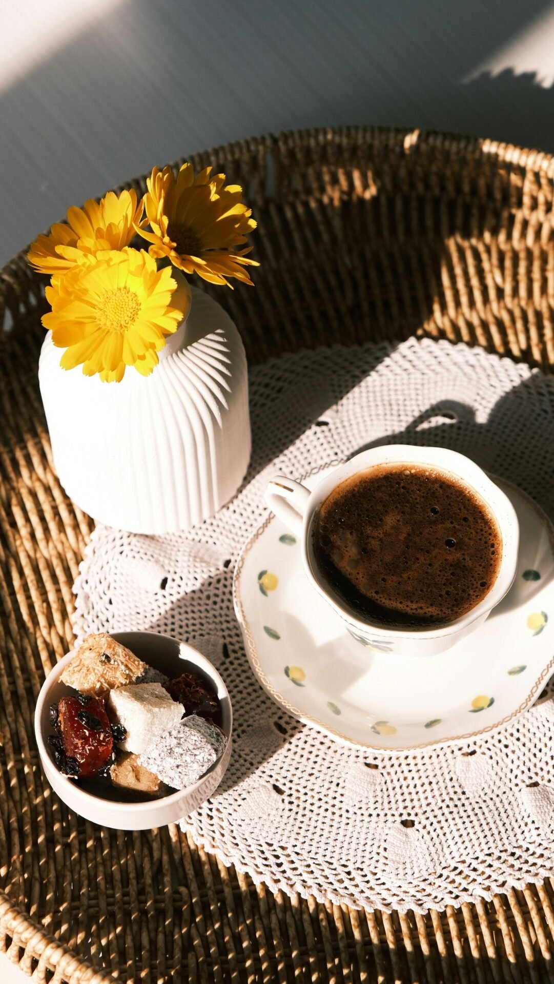 Eine Tasse Kaffee, Süßigkeiten und Blumen laden dazu ein, Prioritäten auf einem gemütlichen geflochtenen Tablett zu setzen.
