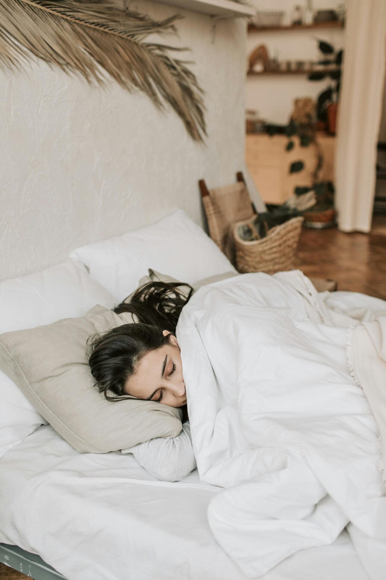Eine Frau liegt im Bett und schläft lächelnd und zufrieden - es wirkt sehr gemütlich.
