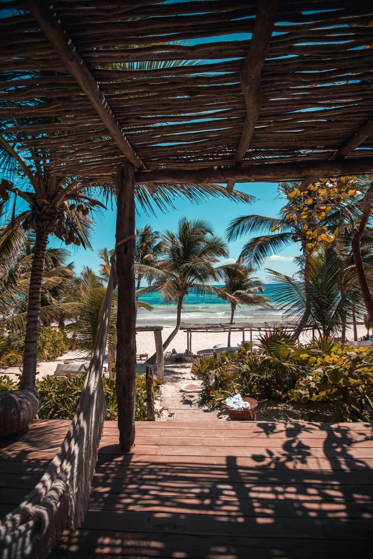 Eine schattige Holzterrasse lädt zu einer Reise ins Glück am tropischen Strand und dem blauen Ozean ein.
