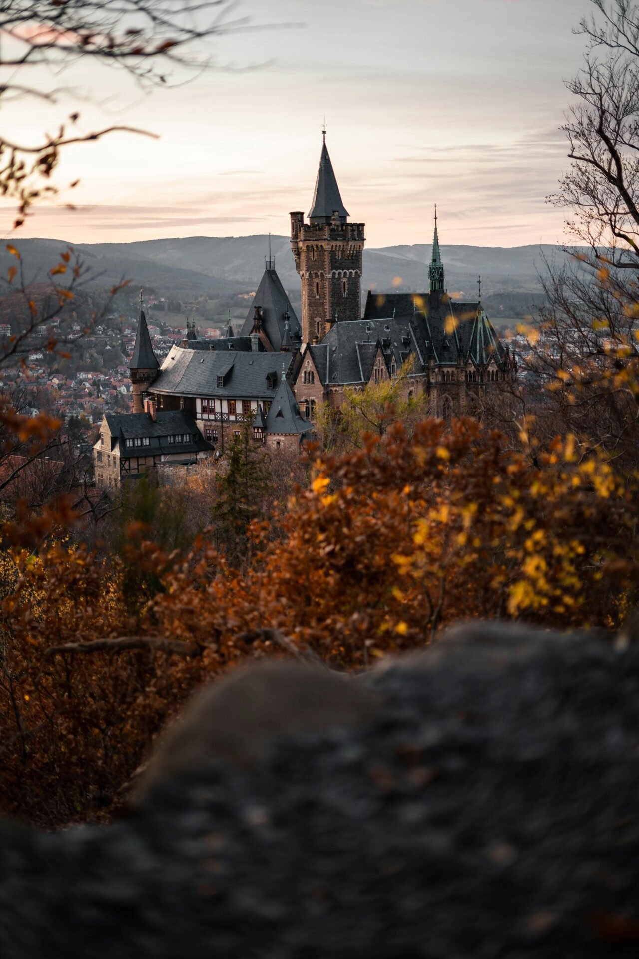 Ein Schloss mit hohen Türmen verspricht eine Reise ins Glück inmitten herbstlicher Bäume bei Sonnenuntergang.