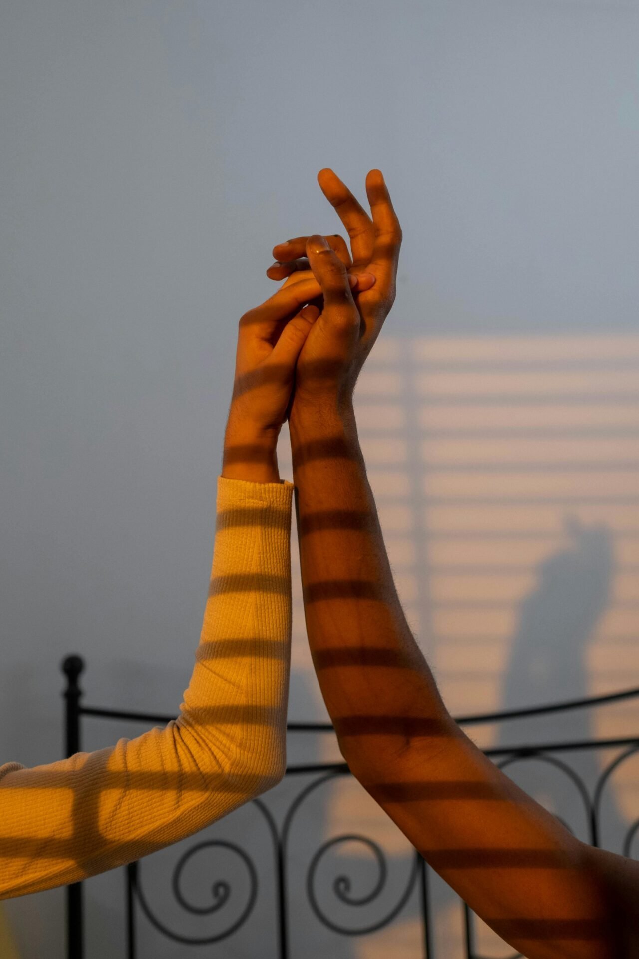 Zwei ineinander verschlungene Hände, gestreifte Schatten, die bei jeder Berührung auf eine starke Persönlichkeit hinweisen.