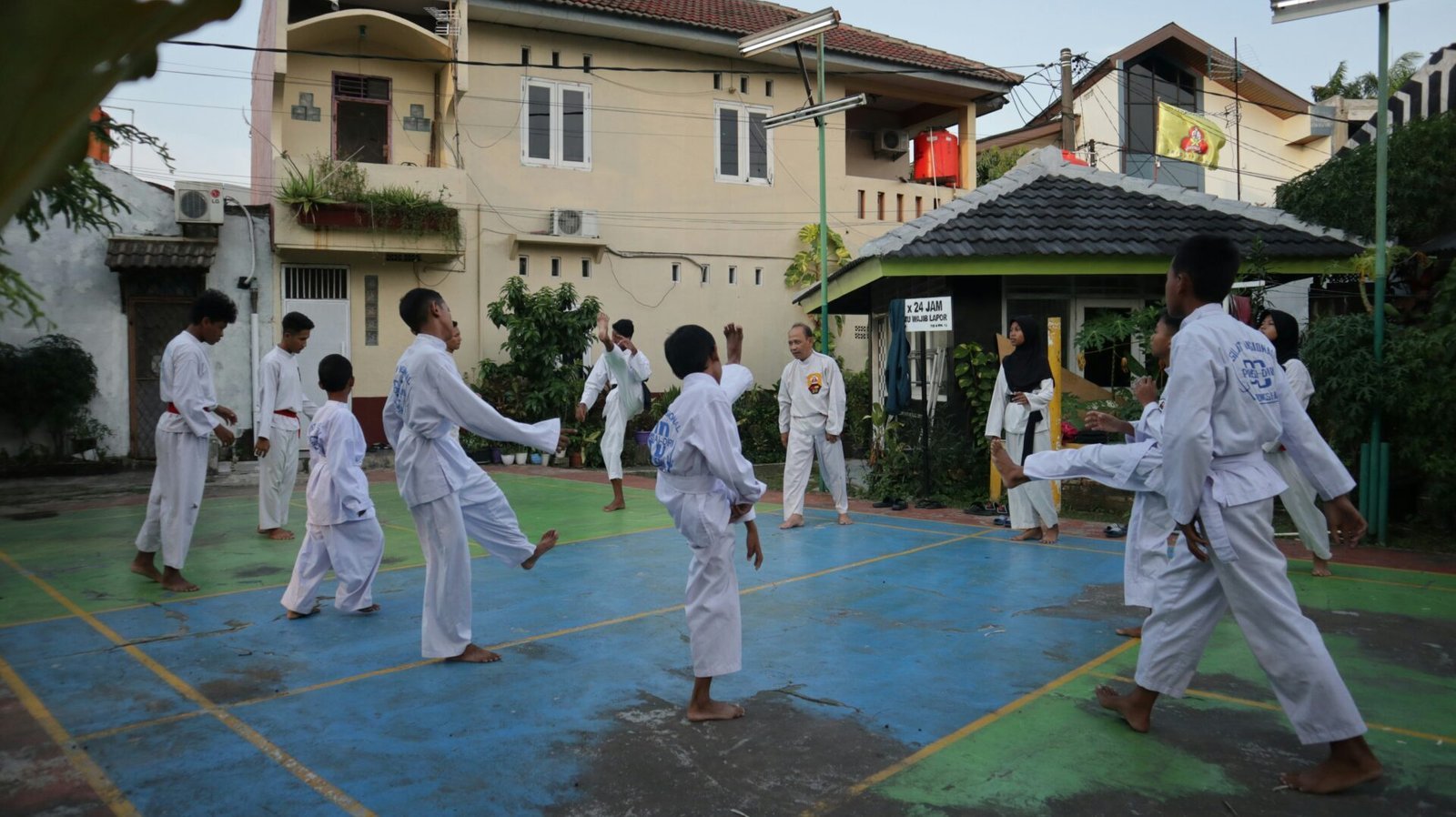Einige Männer trainieren in Kampfsport-Kleidung in einem Hof in Asien mit einem Lehrer.