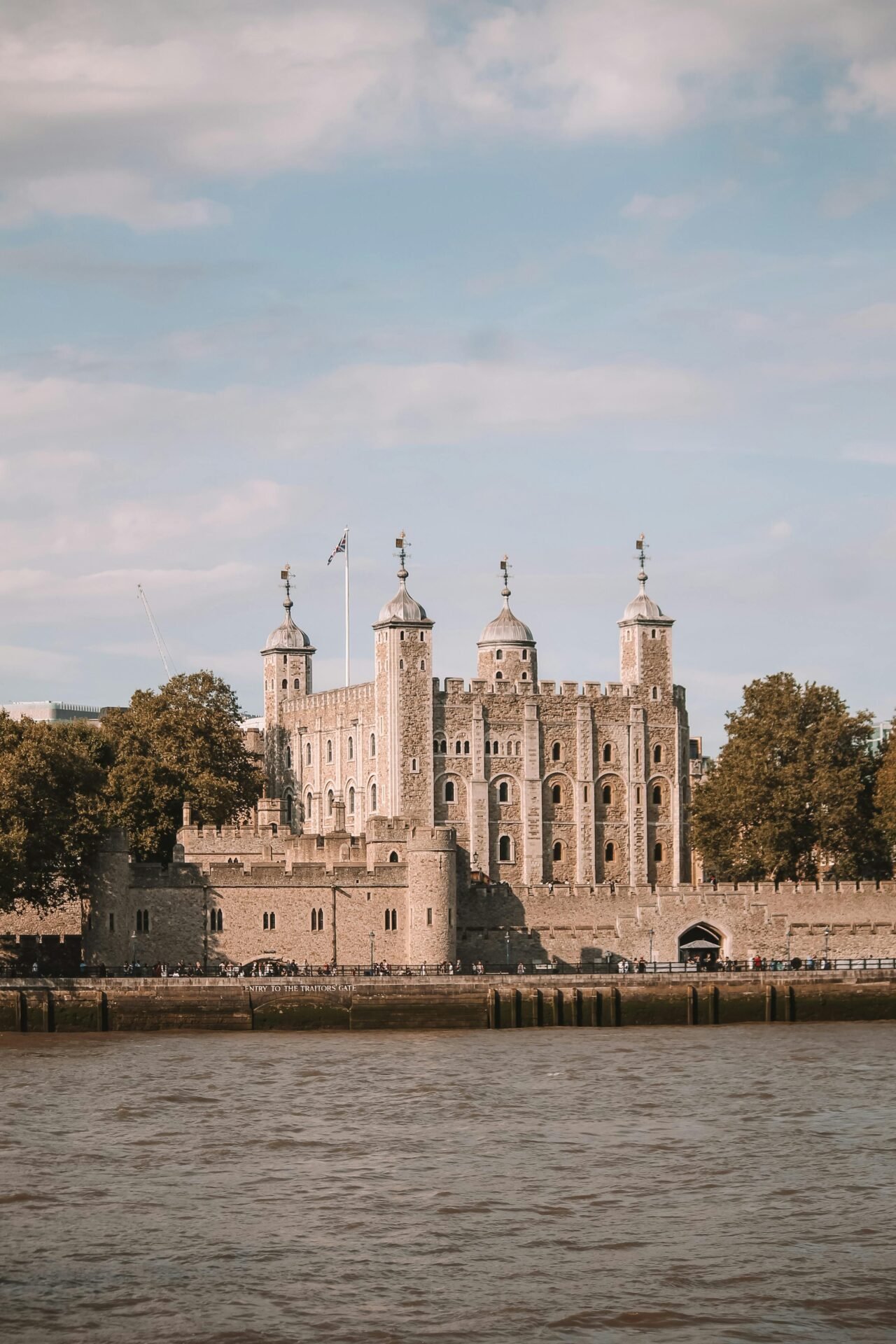 Der Tower of London und Bäume unter blauem Himmel, von der anderen Seite der Themse in London aus gesehen.